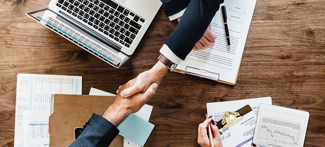 Two people shaking hands over documents