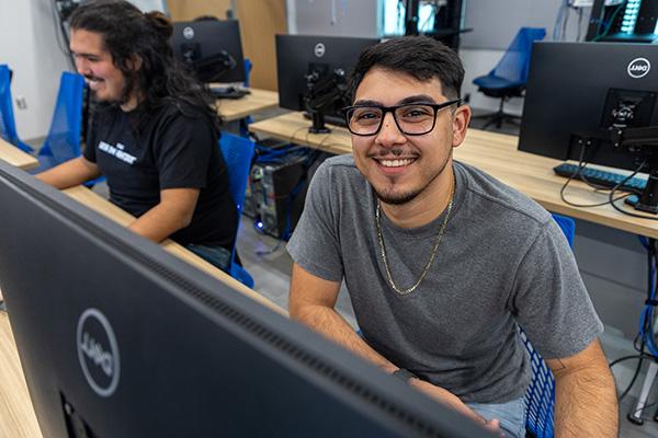 smiling male student using a desktop computer